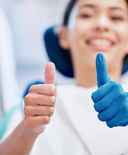 a dental patient and dental team giving a thumbs up sign