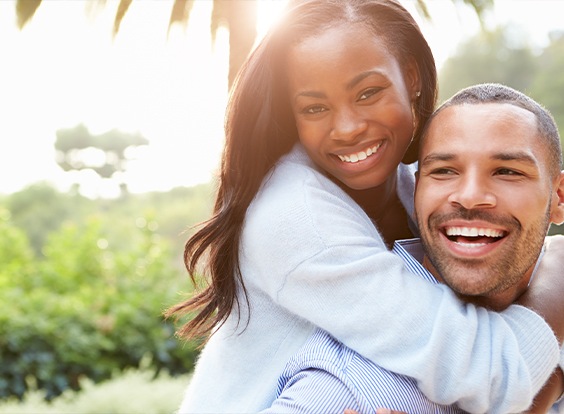 Smiling man and woman holding each other outdoors