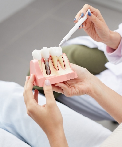 Dentist and patient looking at dental implant model