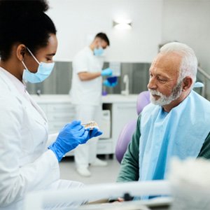 : A dentist explaining denture adjustment to a patient