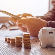 Person using a calculator at their desk with a piggy bank nearby
