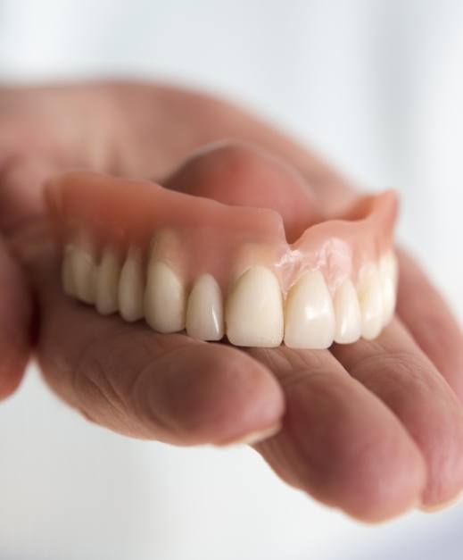 Hand holding a full denture