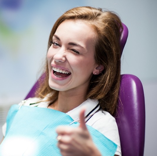 Woman giving thumbs up after dental services