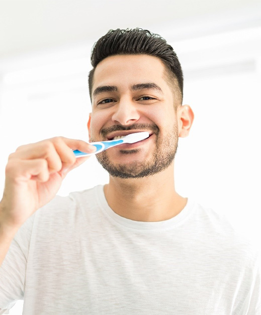 man brushing teeth in bathroom mirror 