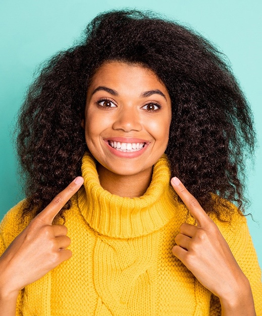 Woman pointing at her smile after teeth whitening in Columbus