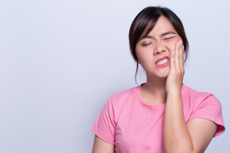 person with a toothache holding their cheek