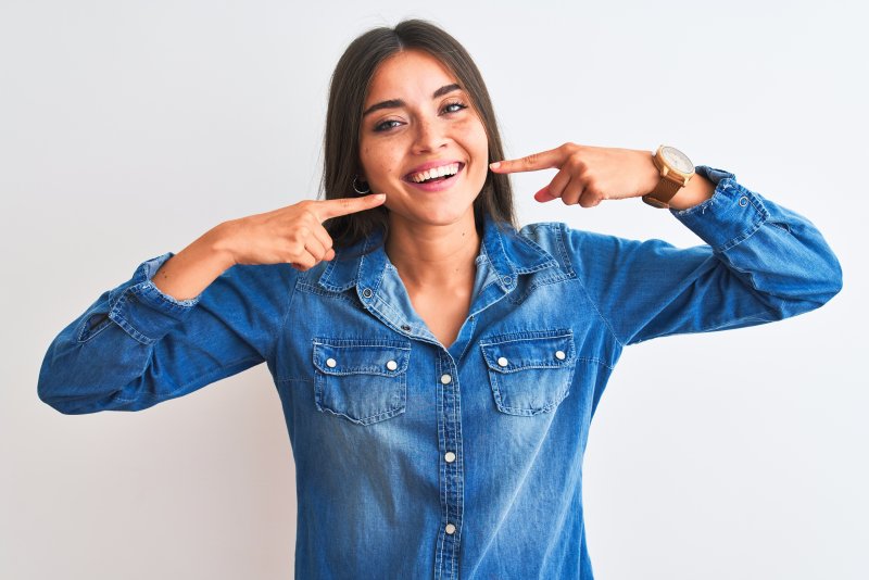 woman smiling and pointing at teeth