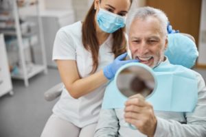 a man smiling at his dental implants in the mirror