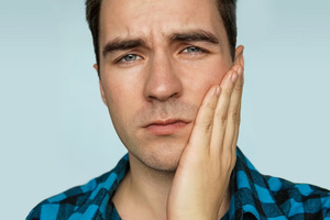 Close-up of man rubbing his jaw looking concerned