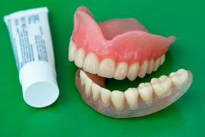 Dentures sitting next to a tube of denture adhesive