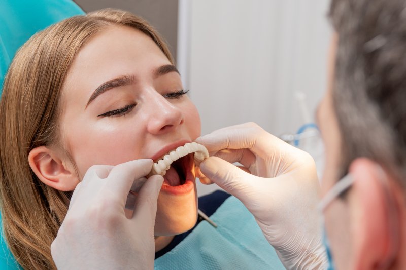 A dentist assessing a young woman for a denture