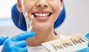 Dentist holding veneers up to patient smiling. 