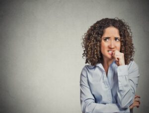 Skeptical looking woman chewing on her fingernail.